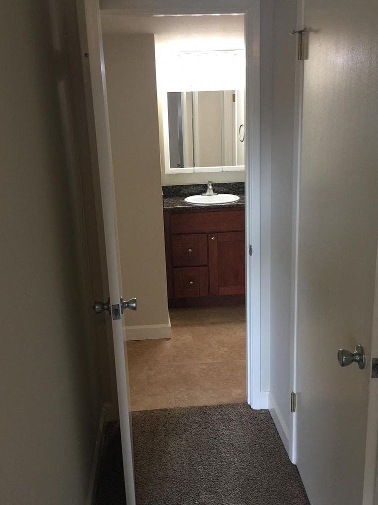 A bathroom with a sink and mirror is visible through a doorway.