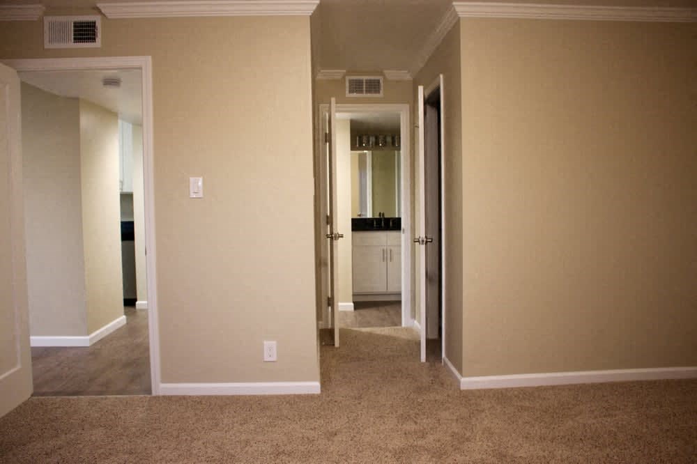 a room with a carpeted floor and a hallway with a closet and a bathroom