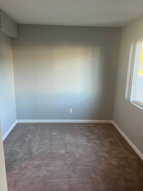 an empty room with a carpet and two windows