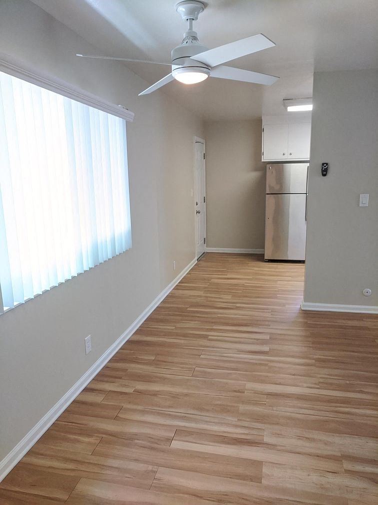 A room with a ceiling fan and wooden flooring.