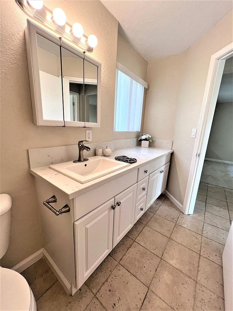 A bathroom with a sink, mirror, and toilet.