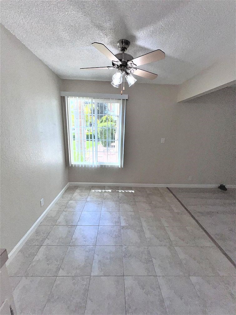 A room with a ceiling fan and a window letting in light.