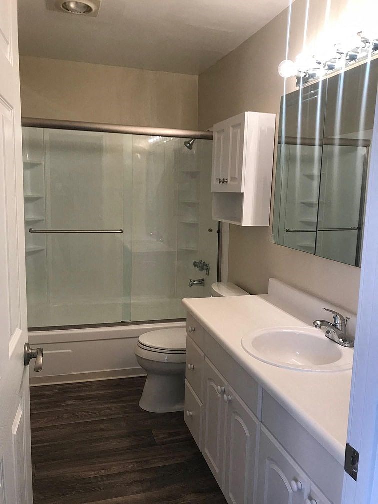 A white bathroom with a toilet, sink, and shower.