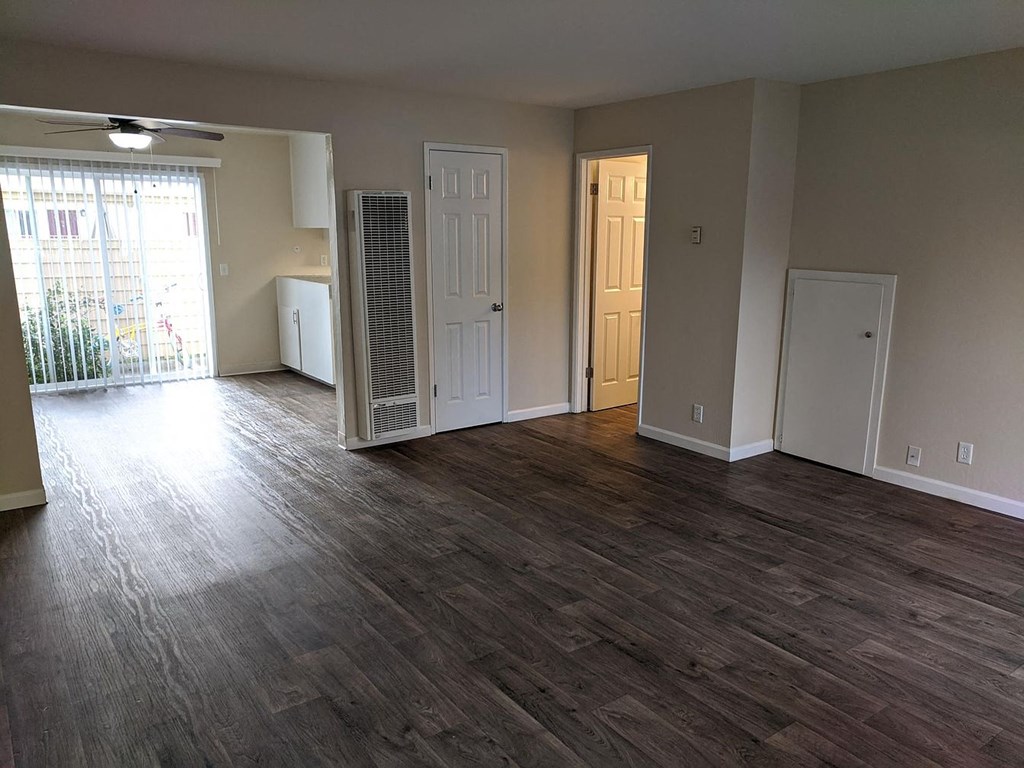 an empty living room with wood flooring and a closet