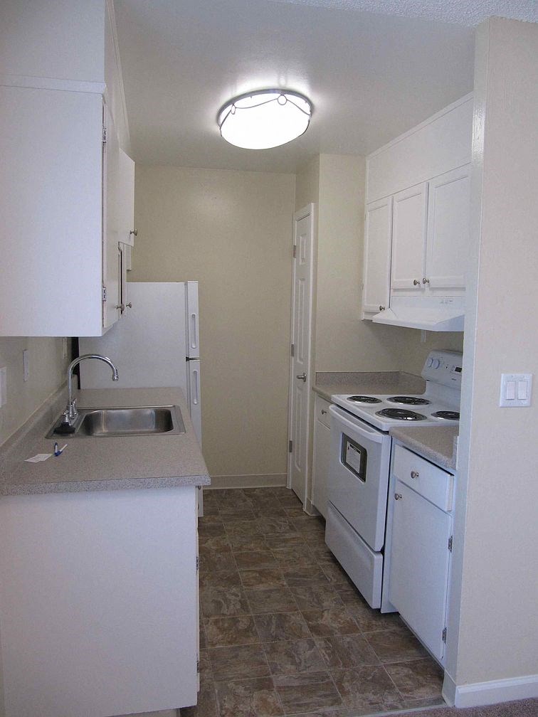 an empty kitchen with white appliances and a sink