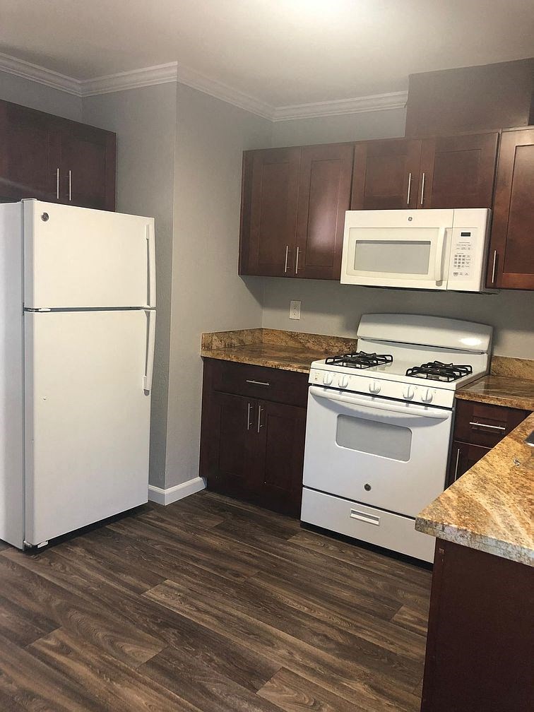 A kitchen with a white fridge, white microwave, and white stove.