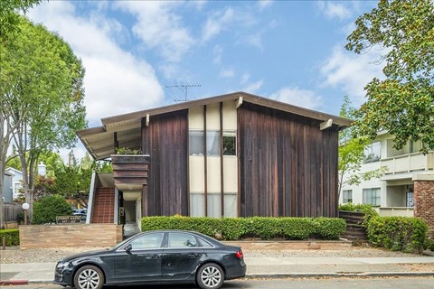 A black car is parked in front of a modern house.
