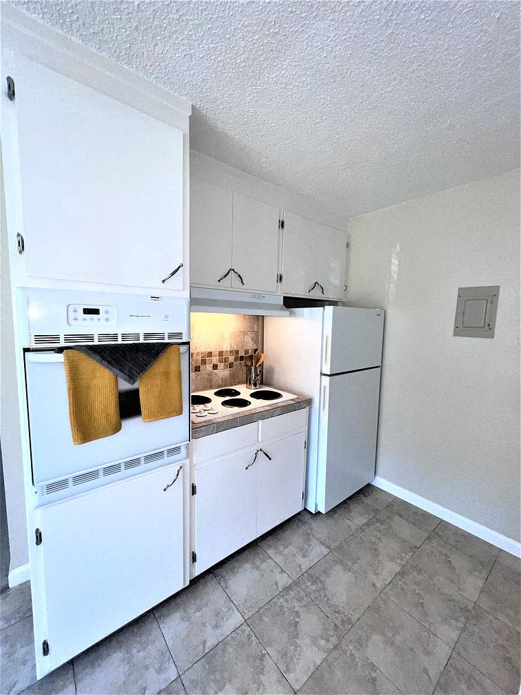 A kitchen with white cabinets and a white oven.