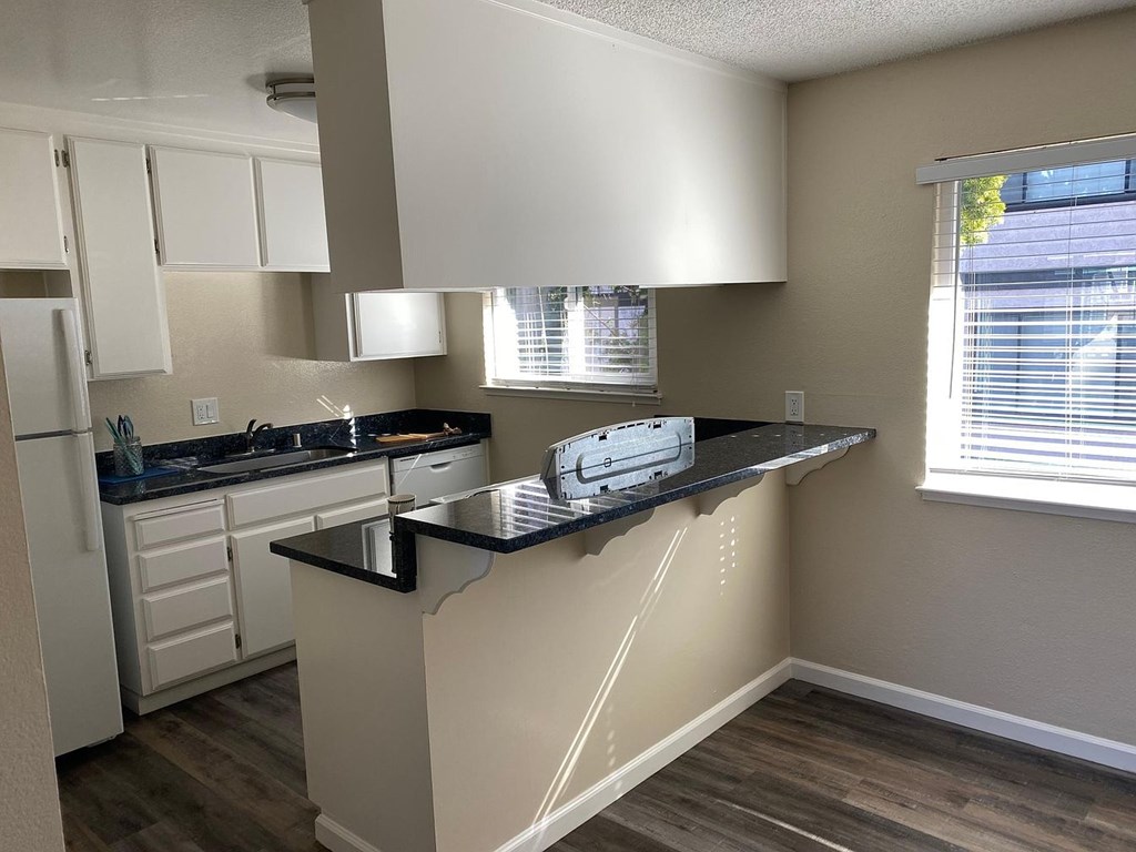 A kitchen with a black countertop and white cabinets.