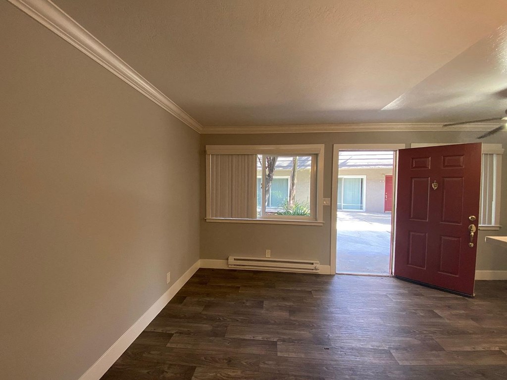 A room with a red door and a window with blinds.