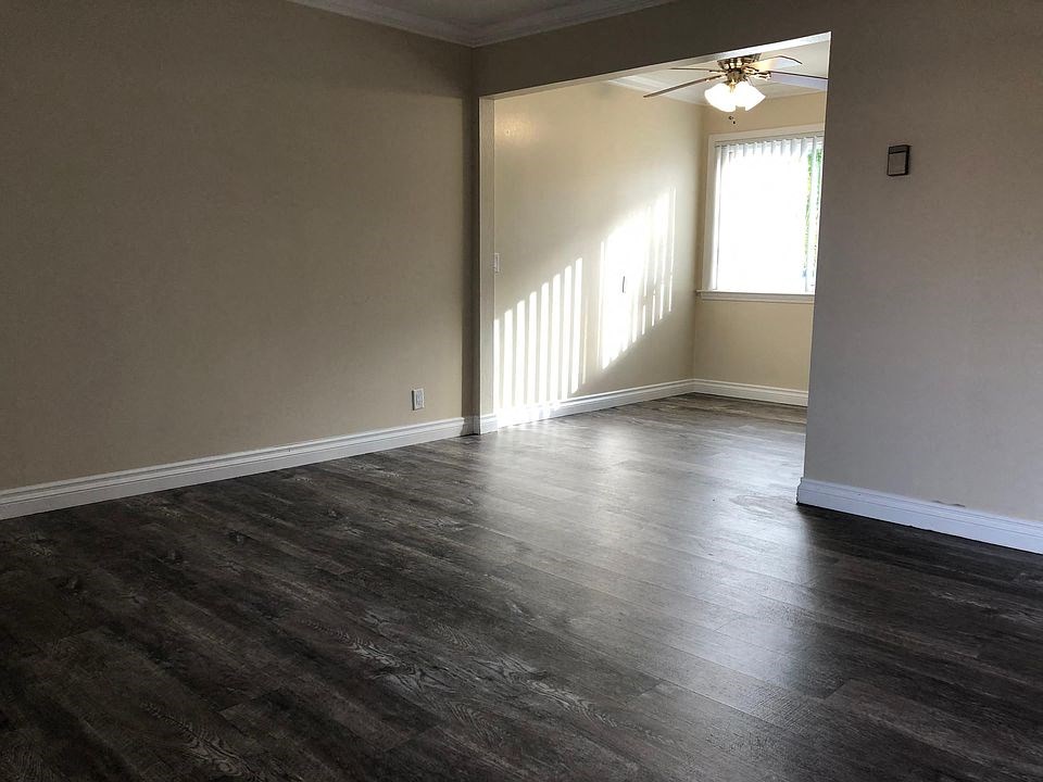 an empty living room with wood floors and a ceiling fan