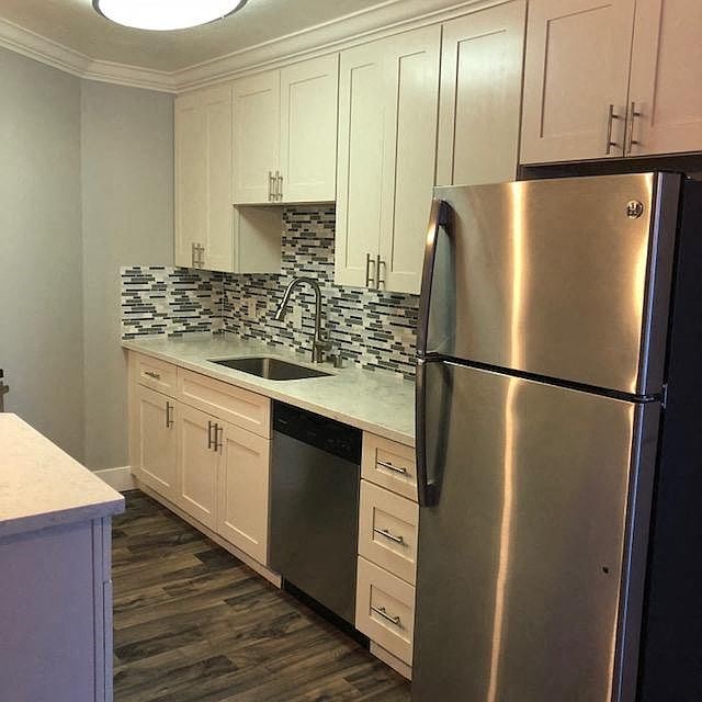 A kitchen with a stainless steel refrigerator and white cabinets.