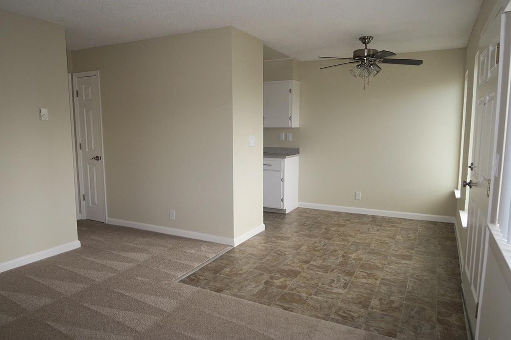 an empty living room with a ceiling fan