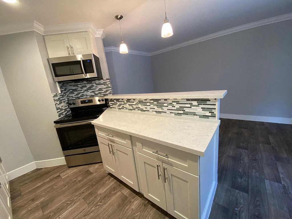 A kitchen with a white counter top and wooden cabinets.