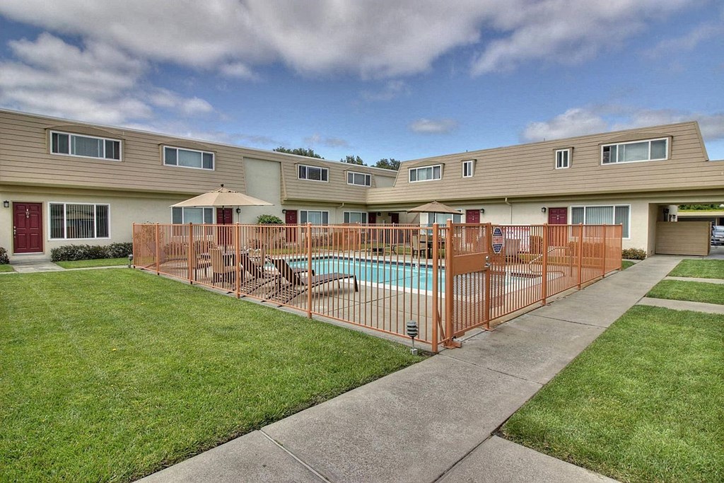 a yard with a swimming pool behind a fence