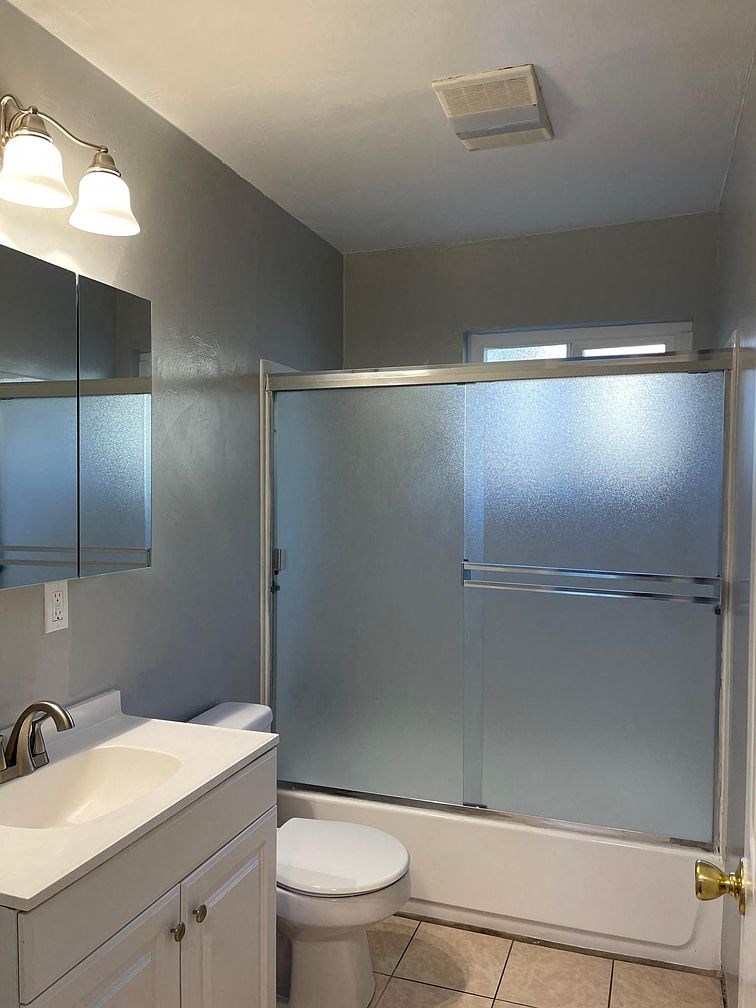 A bathroom with a white toilet, sink, and shower.