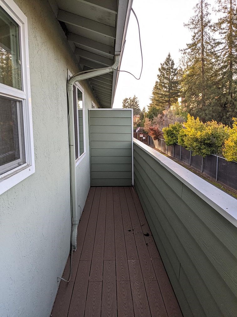 A wooden deck with a white railing and a green shed.
