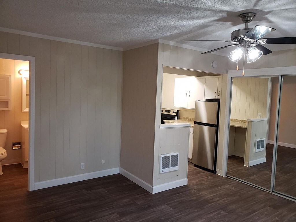 A room with a ceiling fan and a mirror on the wall.