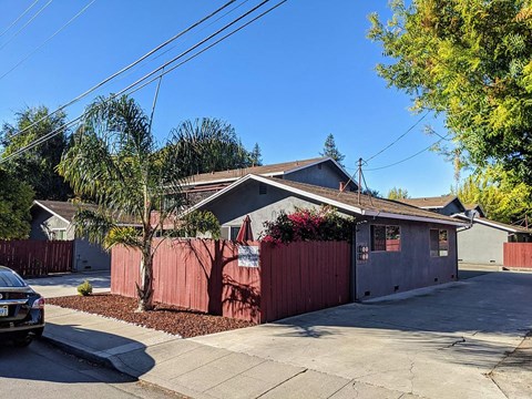 a house with a red fence and a tree in front of it