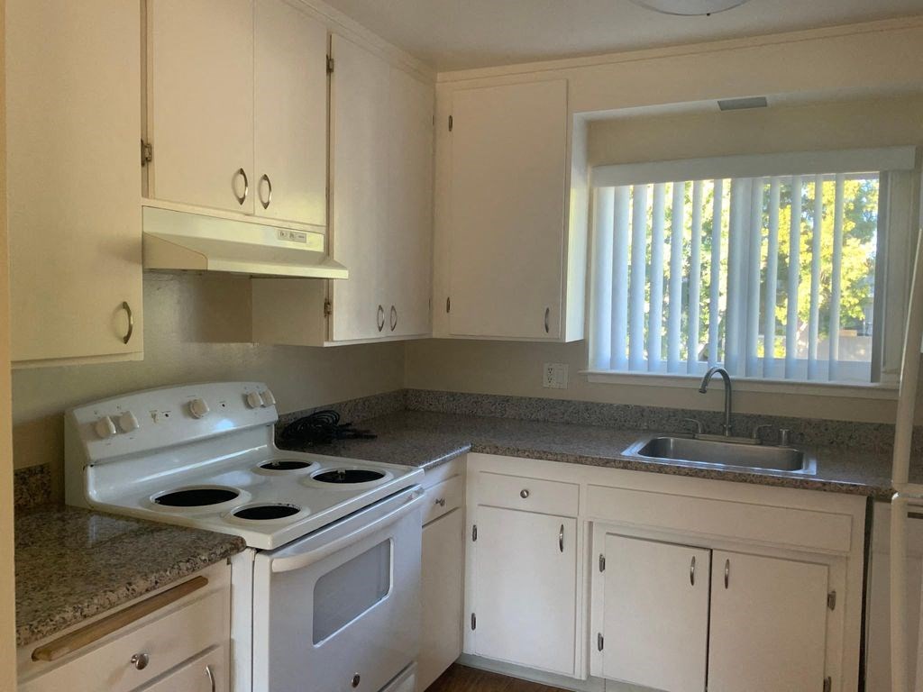 A white kitchen with a stove and cabinets.