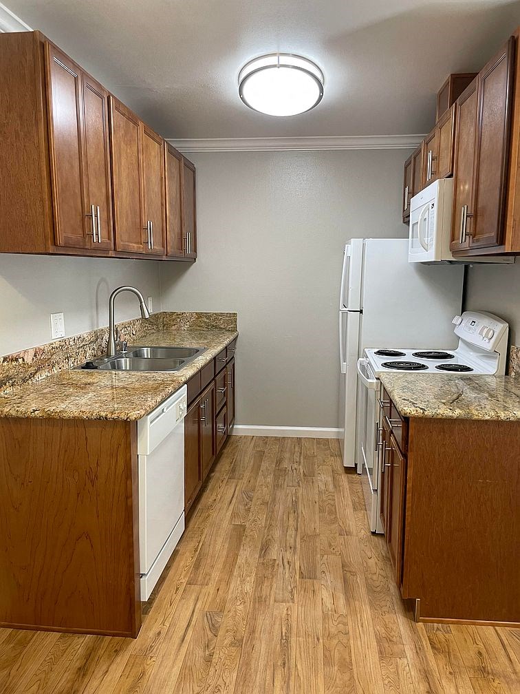 A kitchen with white appliances and wooden cabinets.