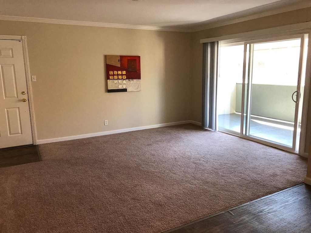 A room with a carpeted floor and a painting on the wall.