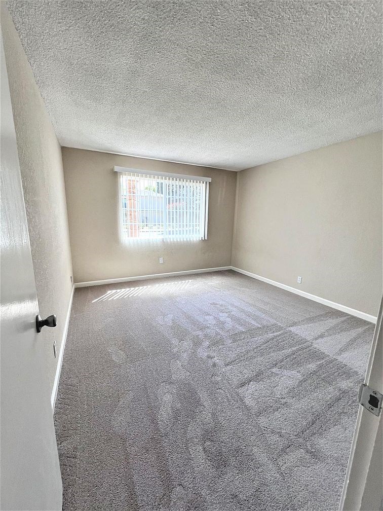 A room with a carpeted floor and a window.