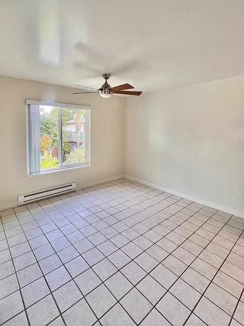 an empty living room with a ceiling fan and tiled floor