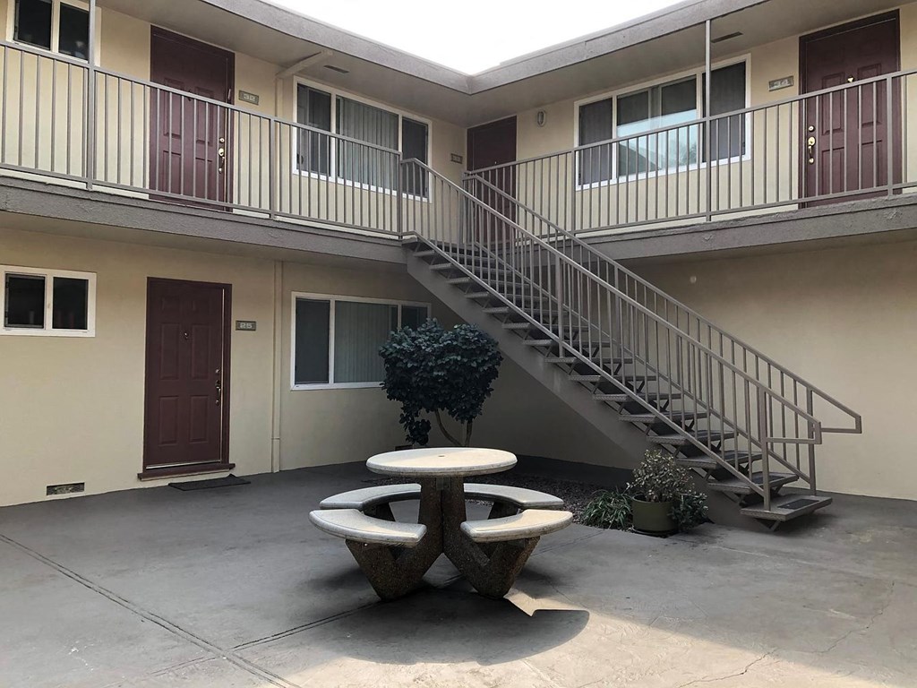an outside view of an apartment building with a table and a staircase