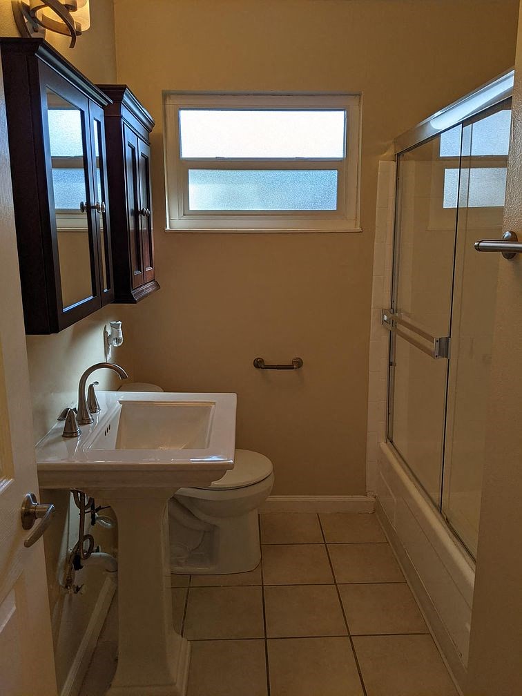 A bathroom with a toilet, sink, and shower.