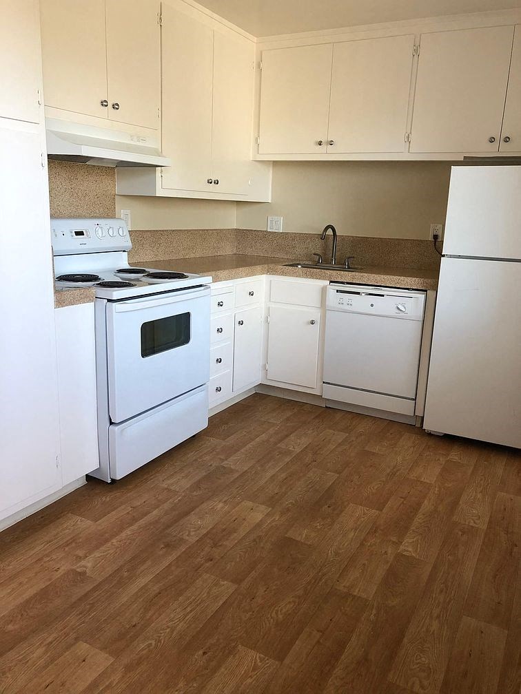 a kitchen with white appliances and a wooden floor