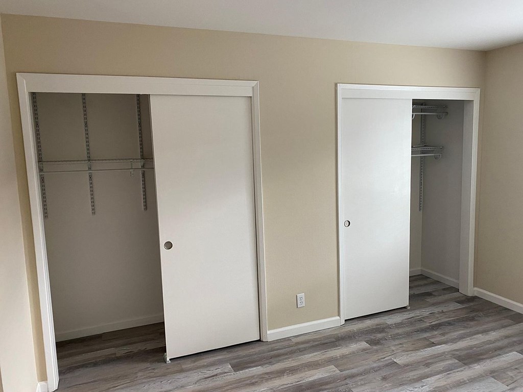 Two white doors in a room with grey flooring.