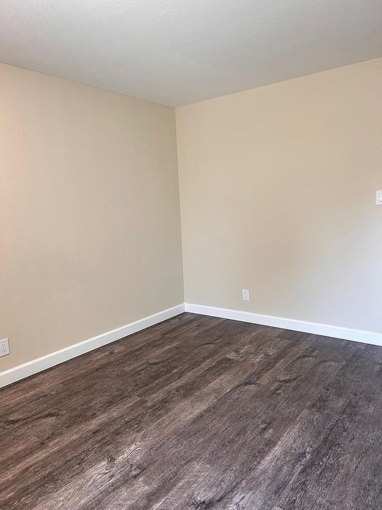 an empty room with wood floors and white walls