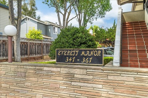 A sign for the Evergift Manor apartment complex is displayed in front of a brick wall.