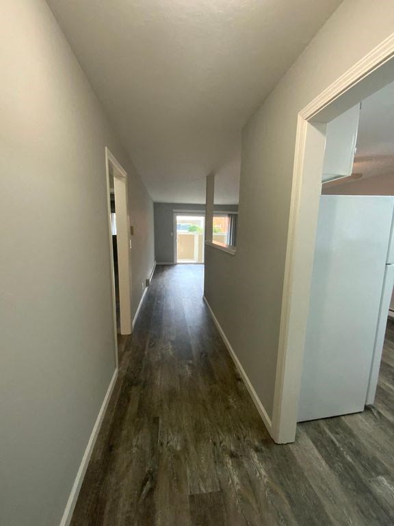 A long hallway with wood floors and white walls.