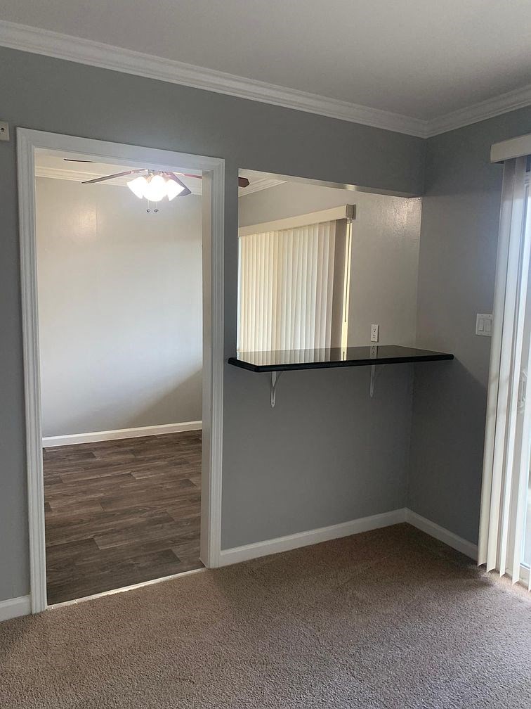 A room with a carpeted floor and a ceiling fan.