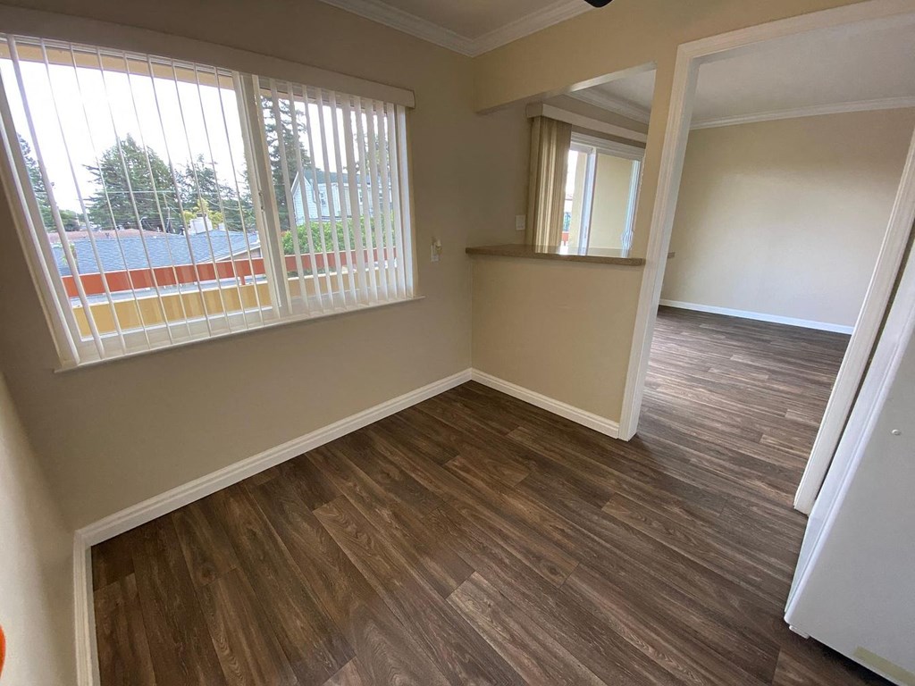 A room with wooden flooring and a window with blinds.