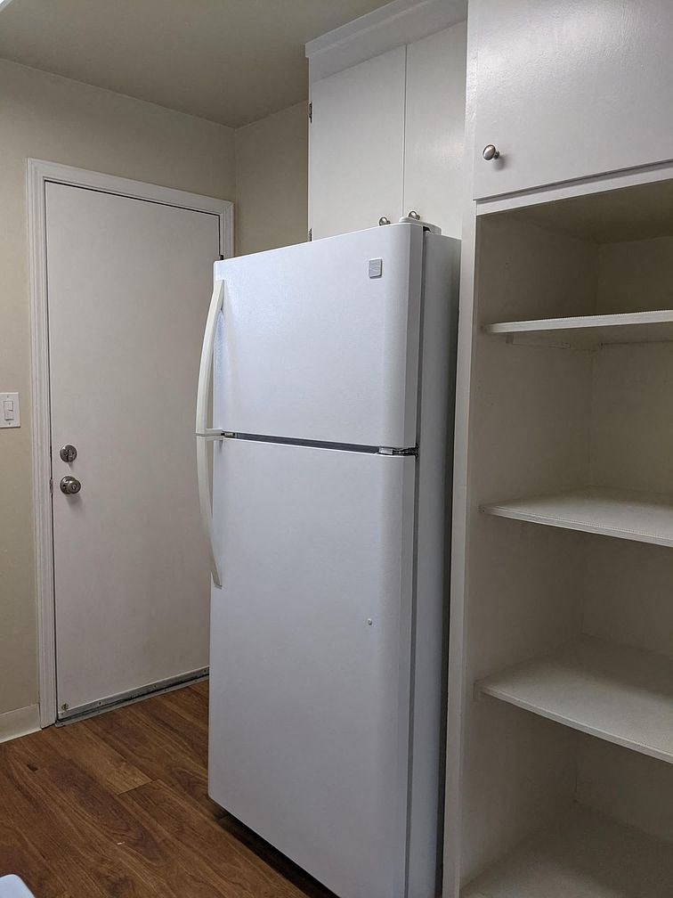 A white refrigerator in a kitchen with a white door.