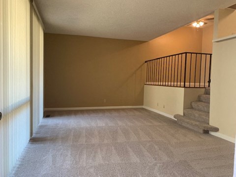 a living room with a staircase and a carpeted floor