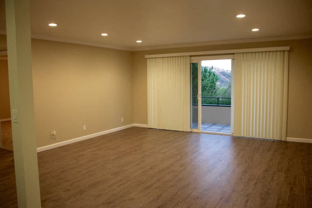 an empty living room with a wood floor and a sliding glass door