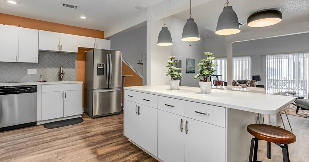 A modern kitchen with white cabinets and a wooden floor.