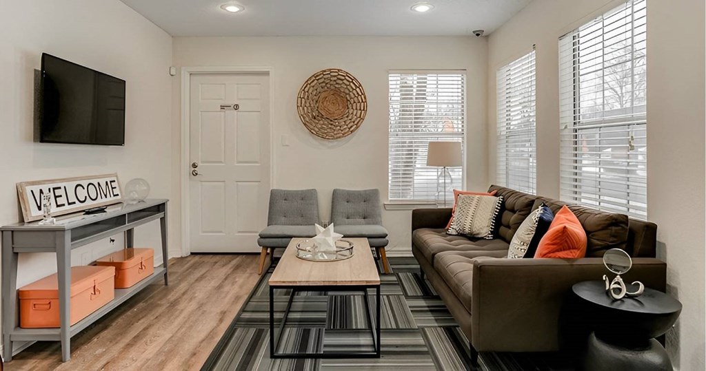 A living room with a brown couch and a wooden floor.