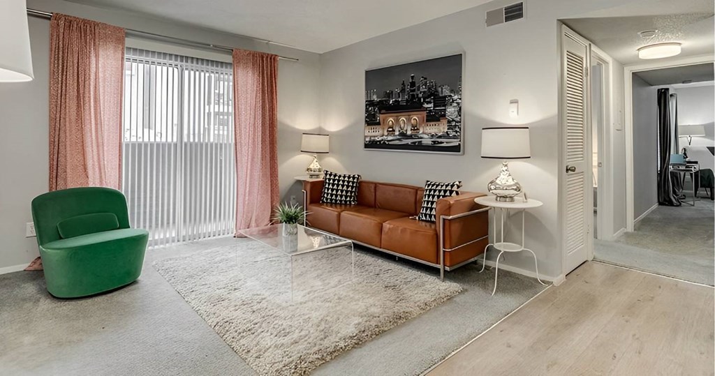 A living room with a green chair, a brown sofa, and a white side table.