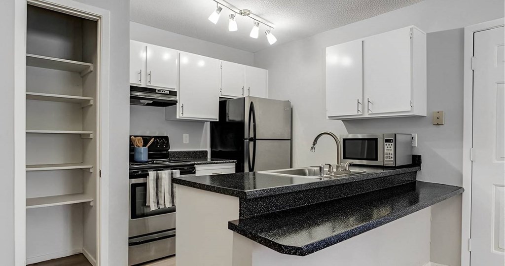A kitchen with black granite countertops and white cabinets.