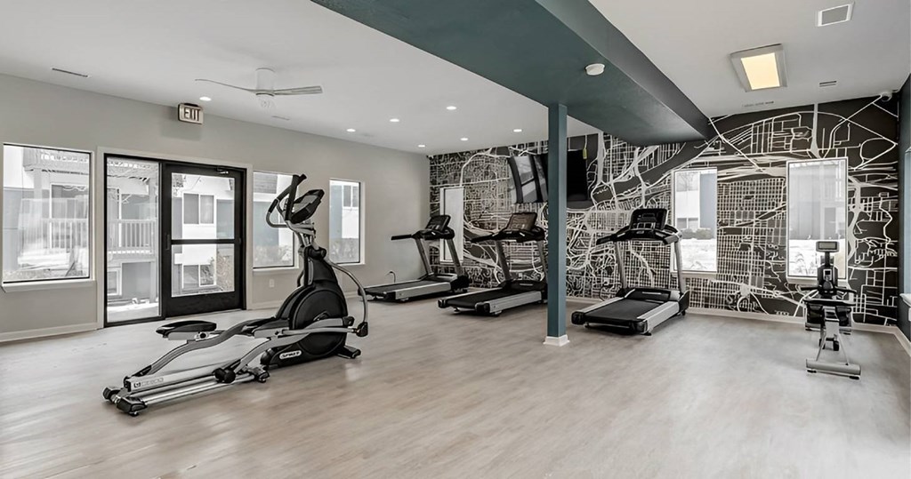 A spacious gym with a variety of equipment including treadmills, stationary bikes, and weight machines.