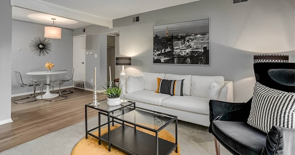 A living room with a white couch, a coffee table, and a black and white photo on the wall.
