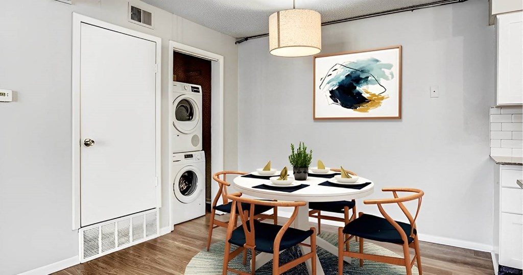 A dining room with a table set for two and a washing machine in the background.