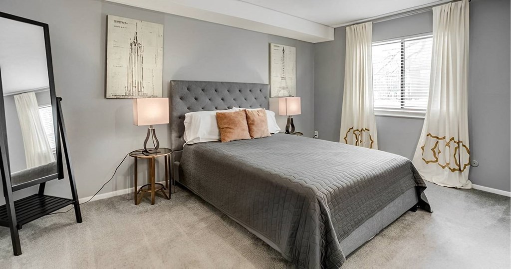 A bedroom with a large bed and two lamps.