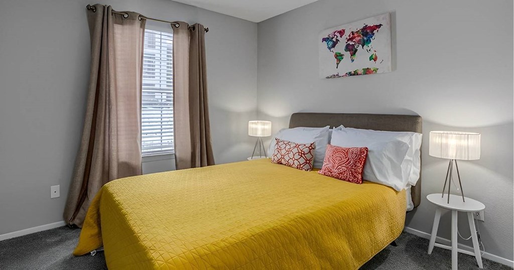 A bedroom with a yellow bedspread and a world map artwork on the wall.
