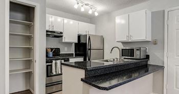 A kitchen with a black granite countertop and white cabinets.